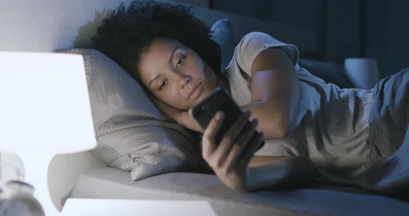 Sleepless woman connecting with her phone at night