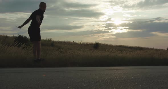 Man Doing Jump Exercises on Skipping Rope on Walkway in Evening and Disappears alt