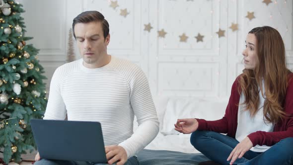 Aggressive Young Woman Hindering Man Working on Computer on Remote Workplace alt