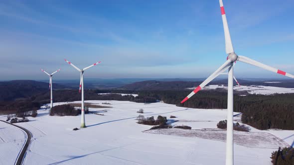 Aerial view of a wind farm. Flying past a rotating wind turbine.