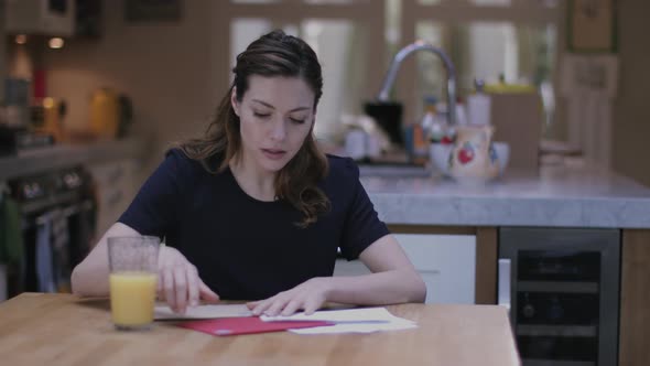 Young adult woman opening bills at home