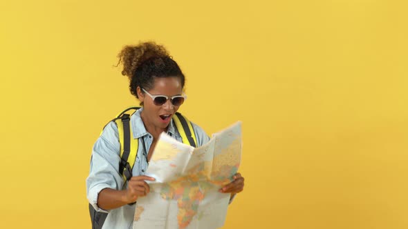 Amazed African American woman tourist doing wow gesture while searching places in world map