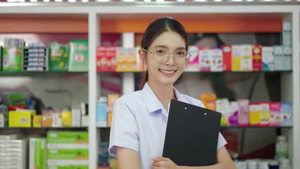 portrait, a beautiful Asian pharmacist is standing and smiling confidently in the pharmacy service.