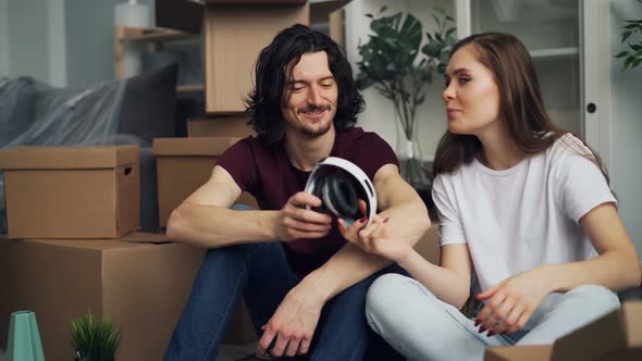 Students Unpacking in New Flat Taking Things From Box Talking During Relocation alt