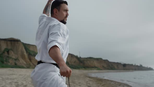 Strong Fighter Practicing Karate on Beach Closeup alt
