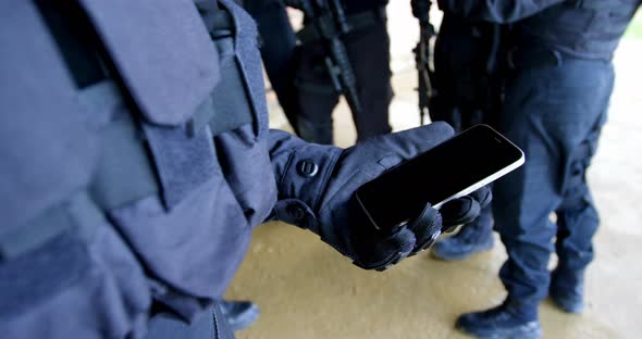 Close-up of military soldier holding mobile phone at military base 4k alt