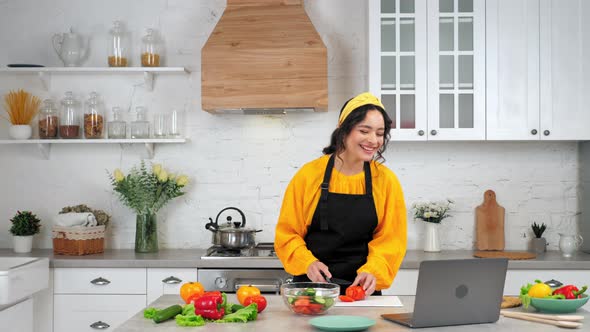 Laughing Woman in Home Kitchen Slices Tomato Listen Chef Study Online Laptop alt