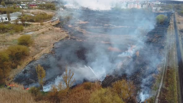 Aerial View of Firefighter in Equipment Extinguish a Forest Fire with a Fire Hose alt