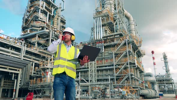 Worker is Talking Over the Radio Near the Oil Refinery Plant alt