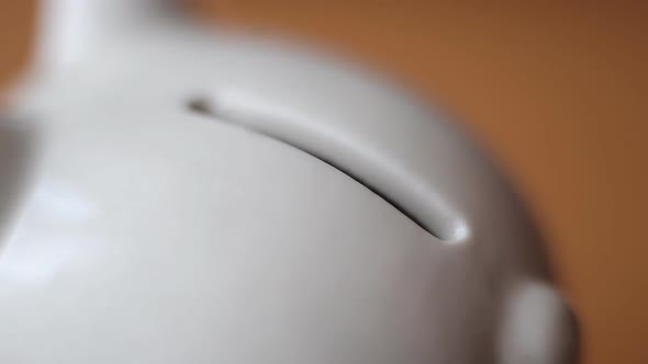 Close up of man hand putting one euro coin in money box or piggy bank
