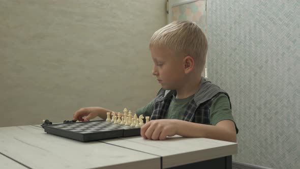 Cute Little Boy Playing Chess at Home