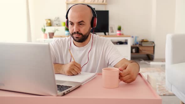 The teenager listens and writes with headphones on the computer	