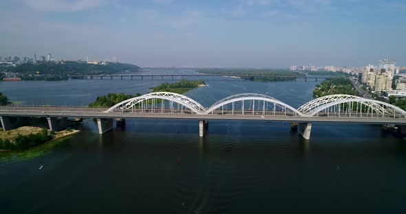 Aerial top view of automobile and railroad Darnitsky bridge across Dnieper river from above alt
