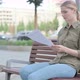 Woman Reacting to Loss while Reading Documents Outdoor