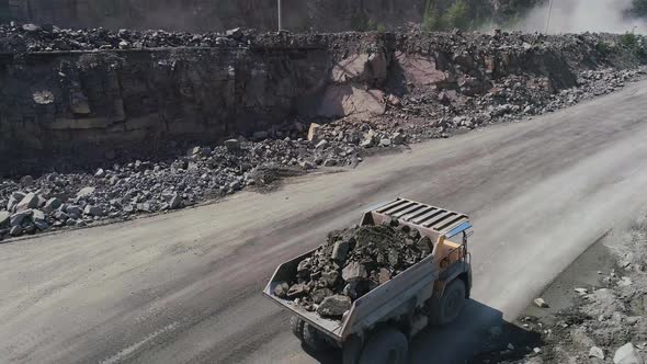 Mining Dump Trucks in Large Granite Open Pit Mine. Close Up Aerial View Drone Chase. Industrial alt