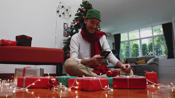 Asian man using mobile taking a photo gift box and upload to the internet in the living room.