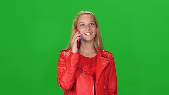 Portrait Blonde Girl Is Calmly Walking and Talking on Mobile Phone at Green Screen. Chroma Key alt