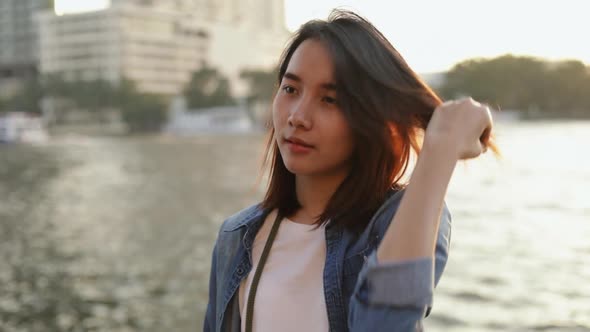 Attractive young Asian female feeling lonely standing beside Chao Phraya river in Thailand.