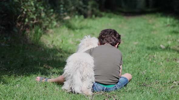 Boy and his dog hugging and playing around in the garden