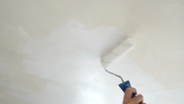 Worker Paints The Ceiling With White Paint, Repairs An Apartment