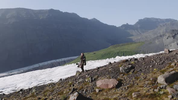 Travelling Man Hiking Down Rocky Hillside By Glacier alt