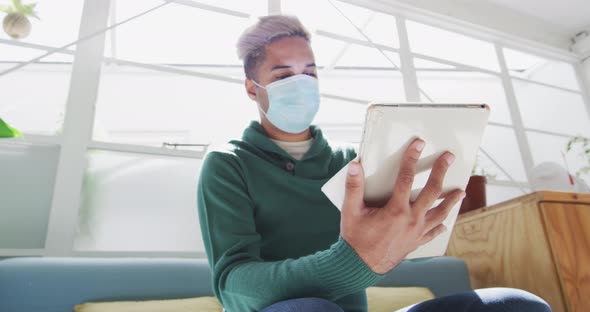 Man wearing face mask wiping his digital tablet with a tissue alt