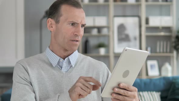 Middle Aged Man Reacting to Loss while Using Tablet alt