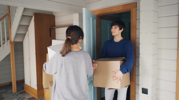 Man and Woman with Carton Boxes Are Opening Door, Entering Their New House alt