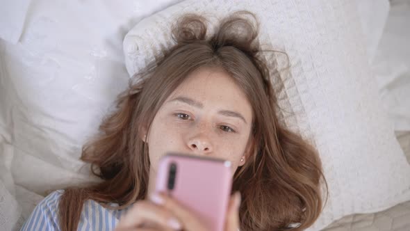 Female Scrolling News Feed on Mobile in Bed