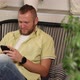 Man Chatting Using Smartphone Sitting on Armchair at Home Types Message with Happy Smile - VideoHive Item for Sale