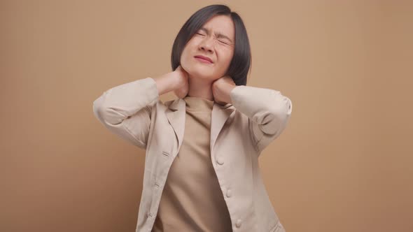 Asian business woman was sick with body pain and standing isolated over beige background. 4K video