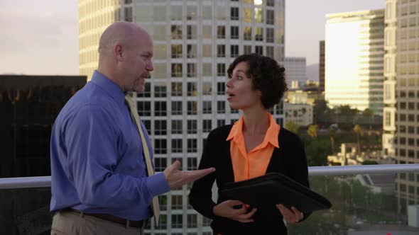 Businesspeople on rooftop look at city