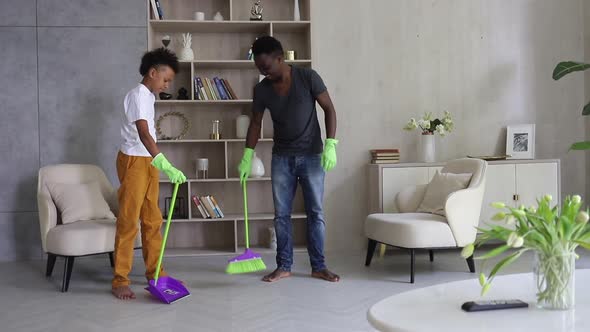Young Dad and Son Cleaning Room and Having Fun in Apartment During Quarantine Spbi alt