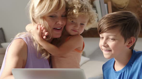 Happy family at home, mother with son and daughter have fun using computer