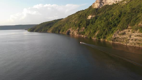 Aerial drone shot: motorboat floating the huge river along the bank.