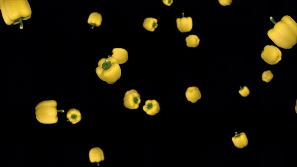 Falling yellow sweet paprikas on a black background
