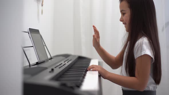 A Little Girl Learns to Play the Piano From Video Lessons alt