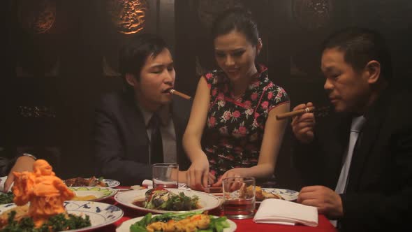 Businessmen drinking and smoking in Chinese restaurant with female on lap alt