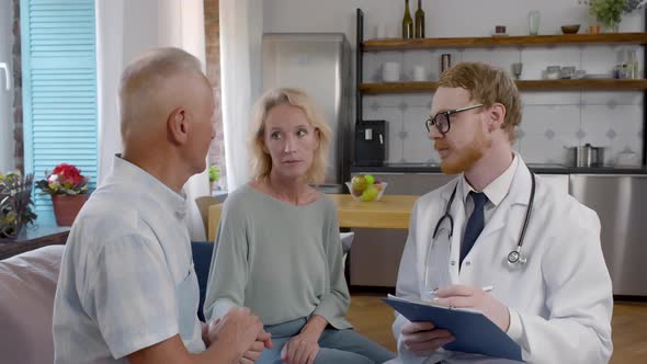 Doctor Consulting Senior Couple During Home Visit alt
