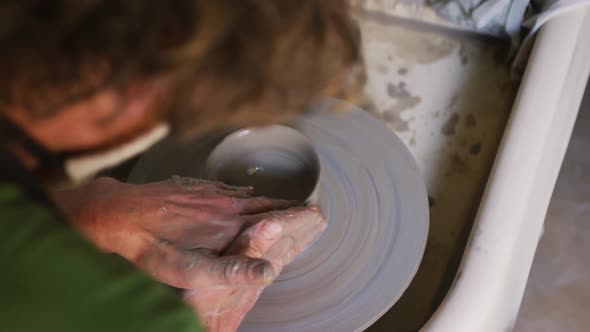 Close up view of male potter creating pottery on on potters wheel at pottery studio alt