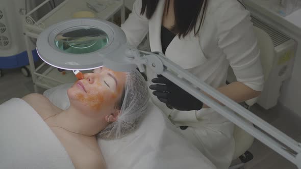 A Woman in a Beauty Salon Applies a Moisturizing Tissue Mask to Her Face alt
