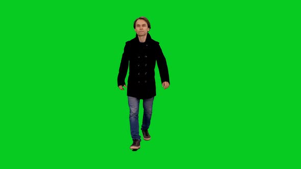 Stylish Man In Black Coat And Jeans Walking Towards The Camera on Green Screen