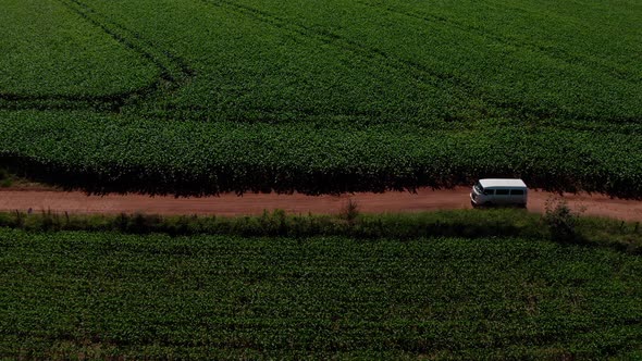 Van driving down a dirt road through a rural, farm landscape - aerial view alt