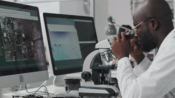 Electronics Engineer Examining Computer Chip with Microscope alt
