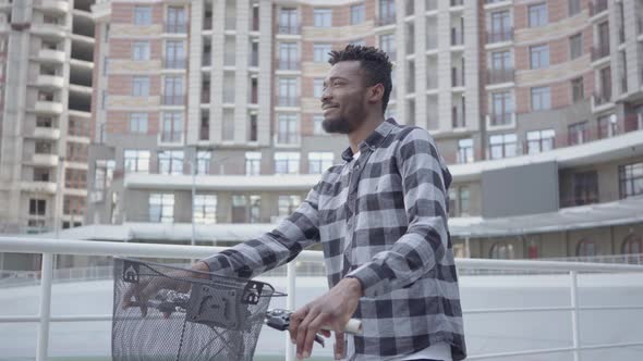 Portrait Handsome African American Man Standing with Bicycle Against the Background of Urban alt