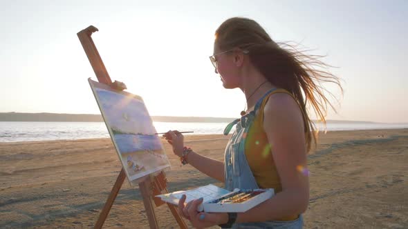 Young Woman Artist Painting Landscape in the Open Air on the Beach Slow Motion alt