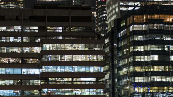 Busy office building windows at night lighting up time lapse