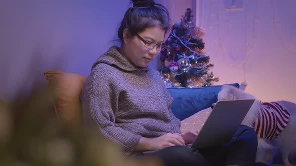working at home asian female woman working with hand use laptop while cuddle play with lap dog alt