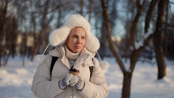 Calm Walk in Winter Day in City Park Handsome Man is Drinking Hot Tea and Scrolling Slowly alt