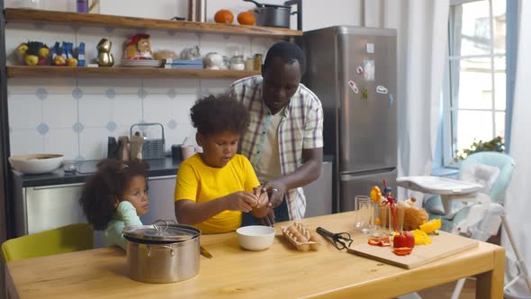 Happy African Father with Children Cooking on Paternity Leave in Kitchen alt
